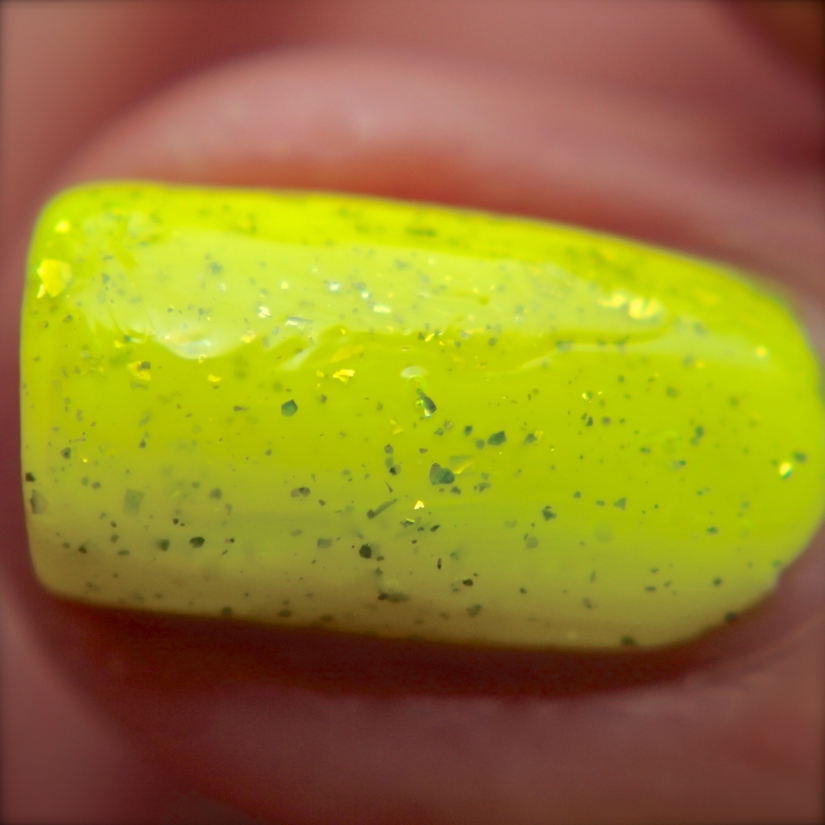 Macro of Electric Sparks. So simple but complex to describe. The highlighter yellow/green jelly base contains various small sizes of silver flakies. This gives them the appearance of having a golden hue, especially in the sun. It stunning! This is the nail with one coat over a white base.